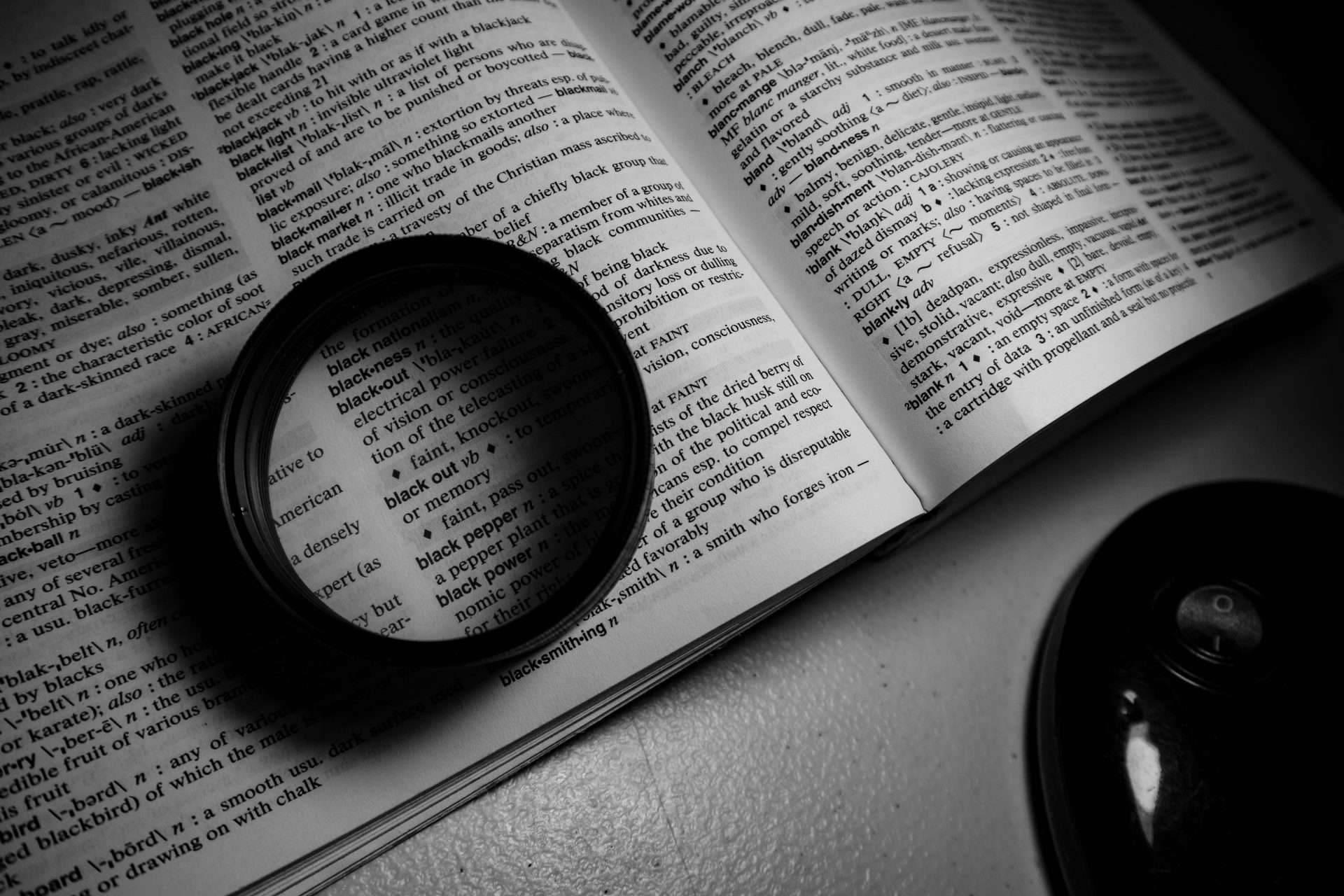 Close-up of an open dictionary with a magnifying lens resting on the page